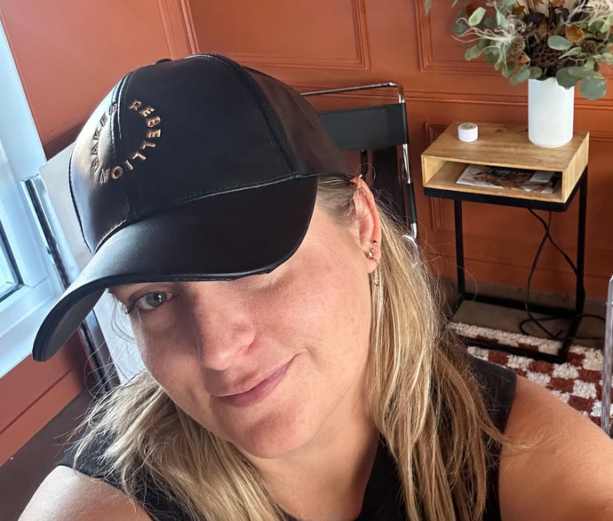 Person wearing a cap with text, sitting in a chair with a checkered pattern.